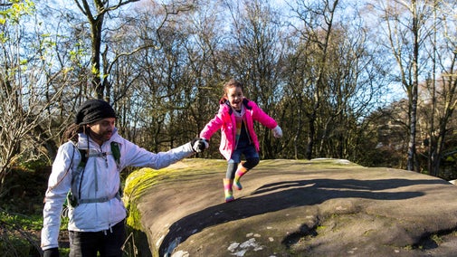 Young girl running along the rocks holding her dads hand